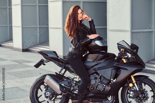 A sexy biker girl sitting on her superbike outside a building. © Fxquadro