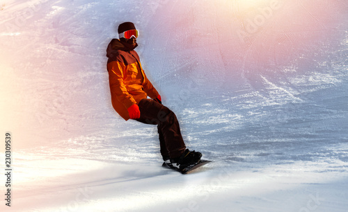 Snowboarder on snowboard  piste running downhill in beautiful Alpine landscape rides through snow, explosion . Freeride snowboarding in  Ski Resort . Blue sky on background. Free space for text