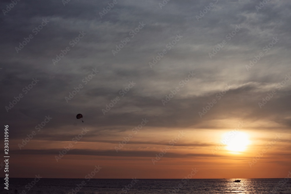 boat pulls a parachute, at sea, at sunset. boat pulls a parachute, at sea, at sunset.