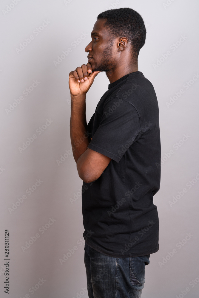 Young African man wearing black shirt against gray background