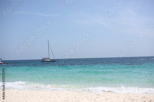 yacht goes by the sea, blue sky, sandy beach.