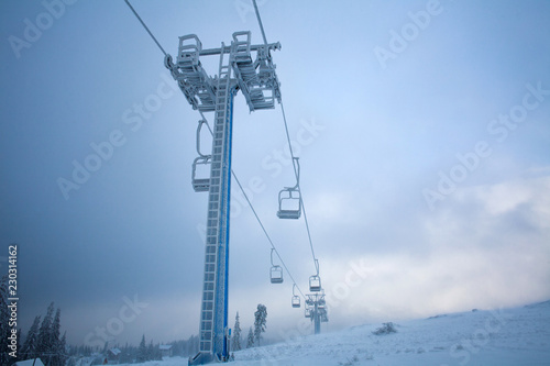 Frozen ski lift covered frost on gloomy day snowy mountains
