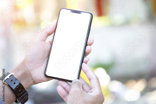 Mock up smartphone of hand holding black mobile phone with blank white screen