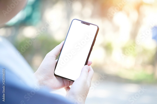 Mock up smartphone of hand holding black mobile phone with blank white screen © Piyaboot