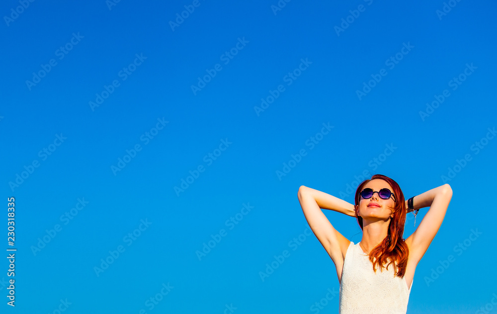 photo of the beautiful young woman on blue sky background photo of the beautiful young woman on blue sky background