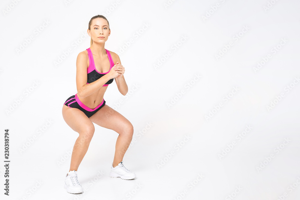Attractive young woman doing sit ups exercise isolated over white background. Attractive young woman doing sit ups exercise isolated over white background.