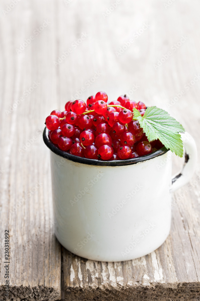 Fresh red currant in old white mug on wooden table Fresh red currant in old white mug on wooden table