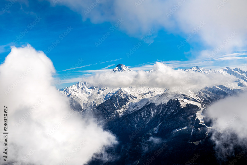 Snow covered Alps mountains peaks among the clouds