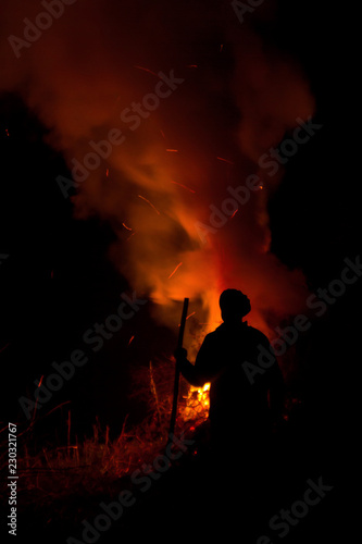 Man silhouette looking at the fire at night