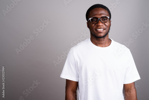 Young African man wearing white shirt and eyeglasses against gra