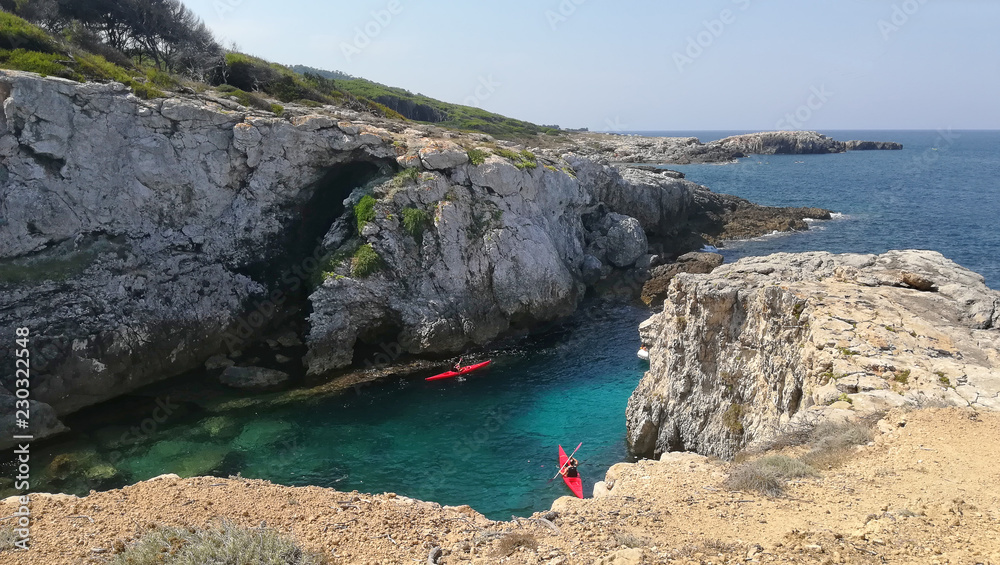 davPuglia, Italy, August 2018, a small round bay in the Tremiti islands. Two canoeists on an excursion