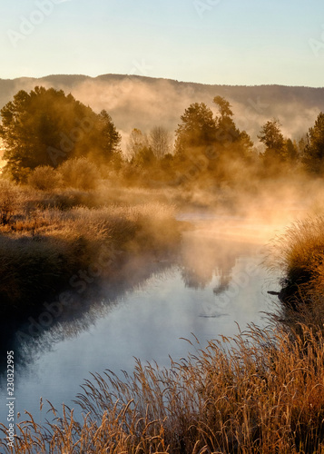 Morning sun burning through the fog on a mountain stream