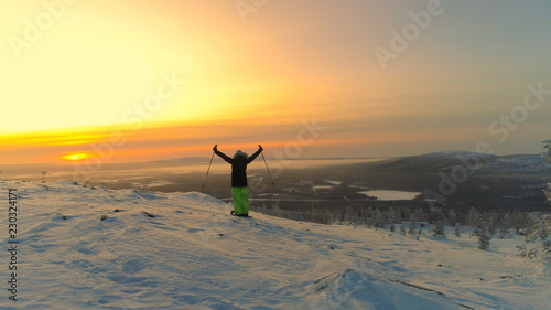 Konstfotografi AERIAL: Unrecognizable female skier looks over the spectacular Lapland at sunset