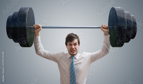 Young businessman in shirt is lifting heavy weights. photo
