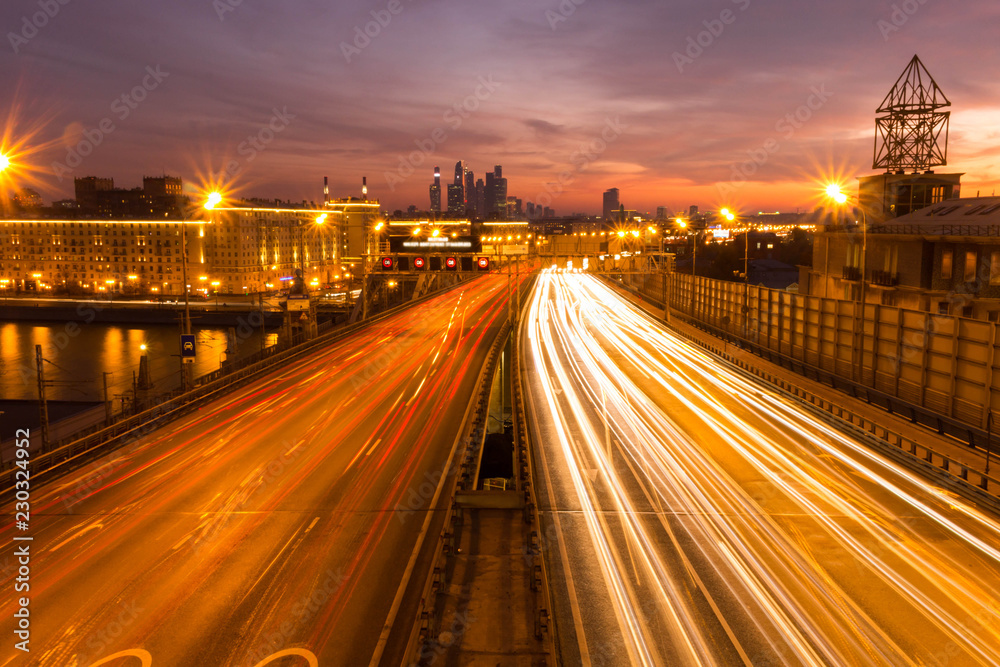 Fototapeta premium Road at night with the lights from many cars on the background of the metropolis.