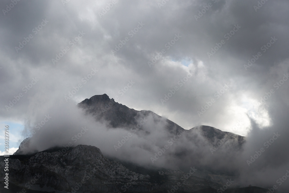Amazing shot of a mountain peak surrounded with light clouds
