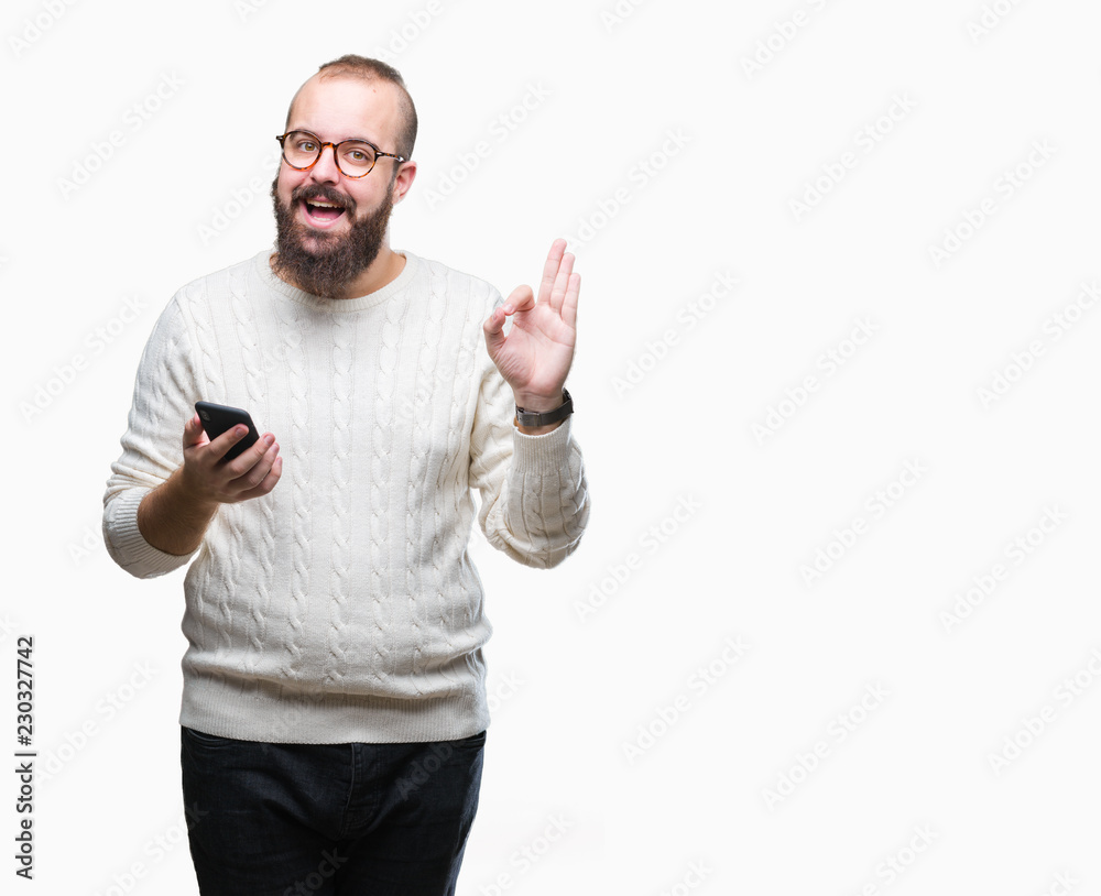 Fototapeta premium Young caucasian hipster man texting sending message using smartphone over isolated background doing ok sign with fingers, excellent symbol