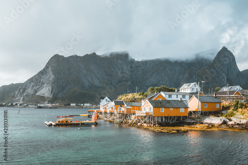 Yellow rorbu houses of Sakrisoy fishing village on a cloudy day with mountains in the background. Lofoten islands, Norway © Mathias
