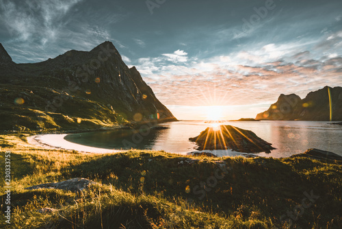 Sunset with sunstar on beach with mountains in the background near Tangstad in lofoten Islands, Norway. Beautiful sandy beach with mountains view.