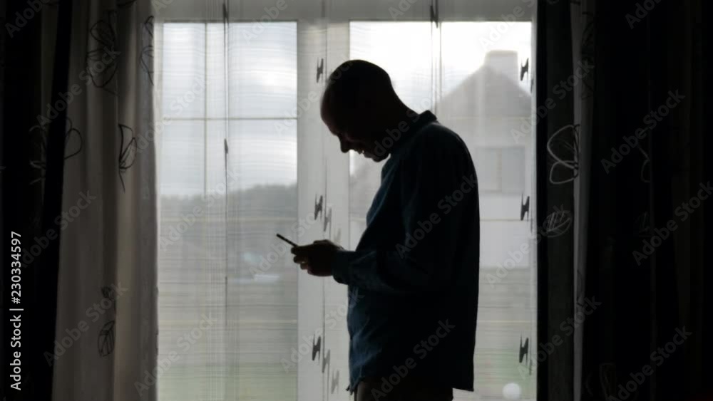 Man Typing a Message Using Mobile Phone. Smiling handsome man writing sms message on the phone.