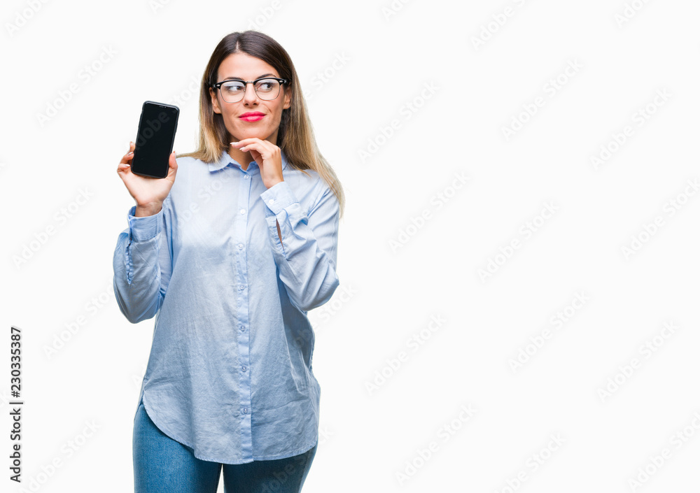 Young beautiful business woman showing blank screen of smartphone over isolated background serious face thinking about question, very confused idea
