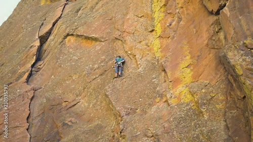 Mountain climber using chalk on his hands for better grip on the vertical rock cliff