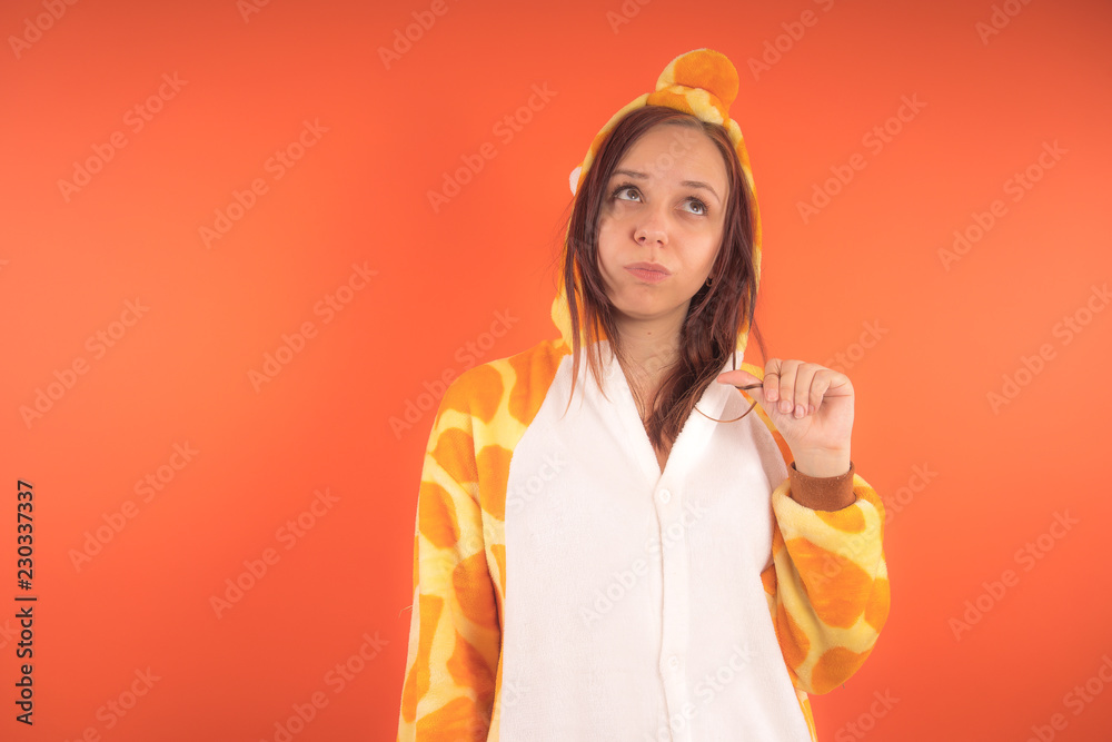 pajamas in the form of a giraffe. emotional portrait of a girl on an orange background. crazy and funny woman in a suit. animator for childrens parties pajamas in the form of a giraffe. emotional portrait of a girl on an orange background. crazy and funny woman in a suit. animator for childrens parties