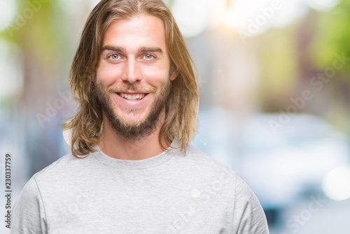 Young handsome man with long hair over isolated background with a happy and cool smile on face. Lucky person.