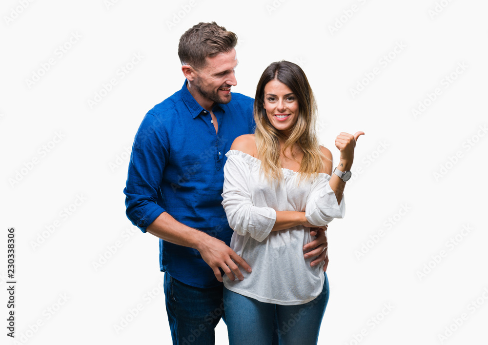 Young couple in love over isolated background smiling with happy face looking and pointing to the side with thumb up. Young couple in love over isolated background smiling with happy face looking and pointing to the side with thumb up.