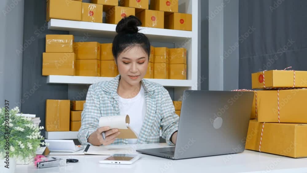 happy woman working with her laptop computer and courier parcel box at home office