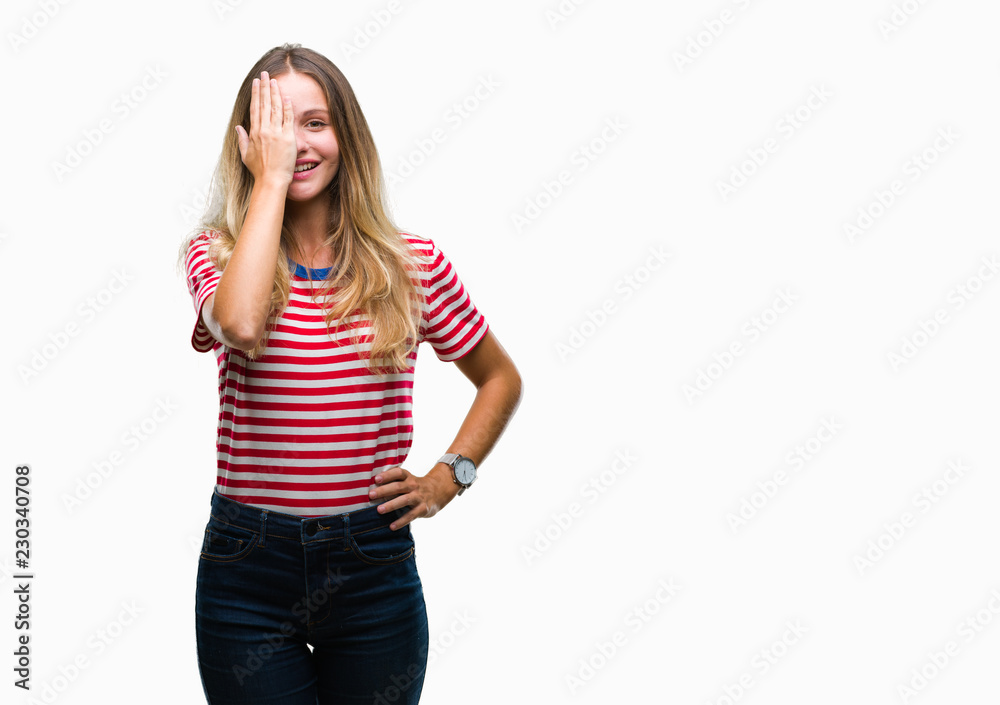 Young beautiful blonde woman over isolated background covering one eye with hand with confident smile on face and surprise emotion. Young beautiful blonde woman over isolated background covering one eye with hand with confident smile on face and surprise emotion.
