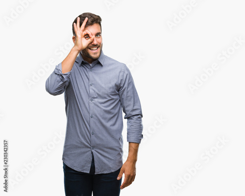 Young handsome man over isolated background doing ok gesture with hand smiling, eye looking through fingers with happy face.