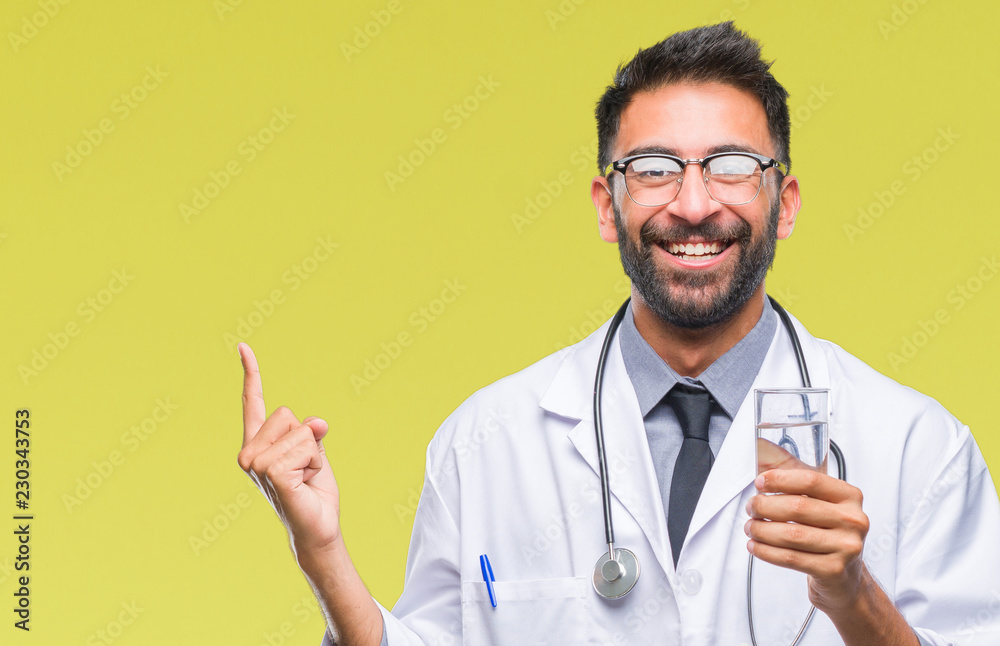 Adult hispanic doctor man drinking glass of water over isolated background very happy pointing with hand and finger to the side Adult hispanic doctor man drinking glass of water over isolated background very happy pointing with hand and finger to the side