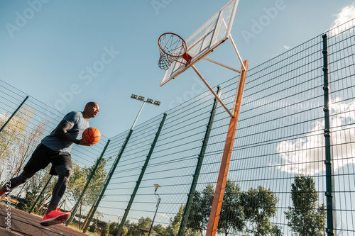Professional workout. Handsome Afro American man holding a ball while having a training © zinkevych