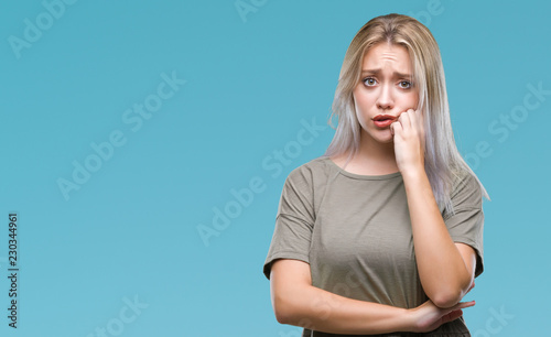 Young blonde woman over isolated background looking stressed and nervous with hands on mouth biting nails. Anxiety problem.