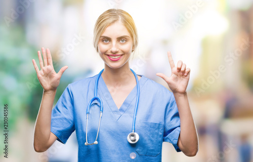 Young beautiful blonde doctor surgeon nurse woman over isolated background showing and pointing up with fingers number seven while smiling confident and happy.