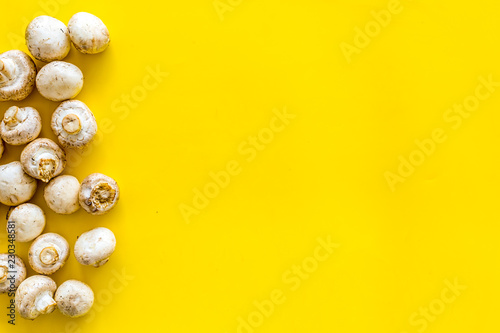 Mushroom champignons. Fresh raw whole champignons on yellow background top view copy space