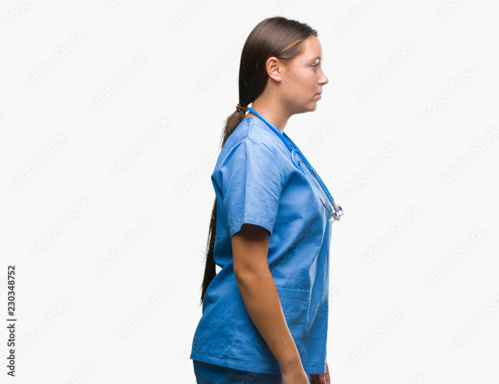 Young caucasian doctor woman wearing medical uniform over isolated background looking to side, relax profile pose with natural face with confident smile. Young caucasian doctor woman wearing medical uniform over isolated background looking to side, relax profile pose with natural face with confident smile.