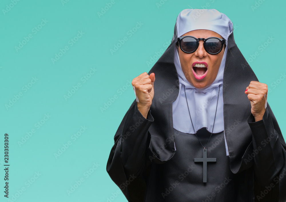 Middle age senior catholic nun woman wearing sunglasses over isolated background celebrating mad and crazy for success with arms raised and closed eyes screaming excited. Winner concept