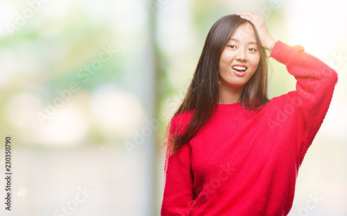 Young asian woman wearing winter sweater over isolated background surprised with hand on head for mistake, remember error. Forgot, bad memory concept.