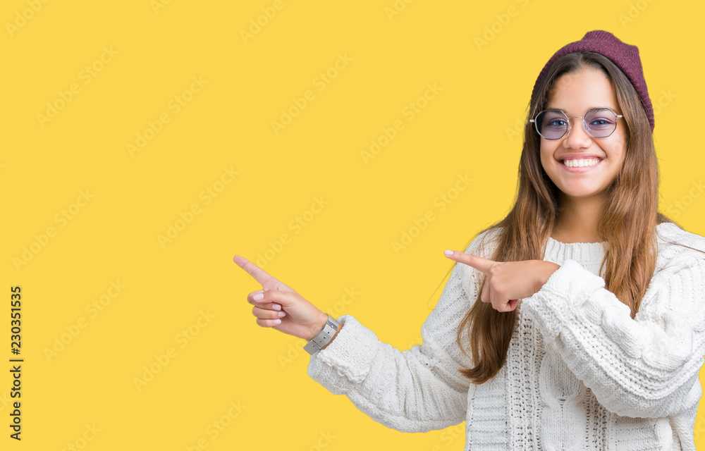 Young beautiful brunette hipster woman wearing sunglasses over isolated background smiling and looking at the camera pointing with two hands and fingers to the side. Young beautiful brunette hipster woman wearing sunglasses over isolated background smiling and looking at the camera pointing with two hands and fingers to the side.