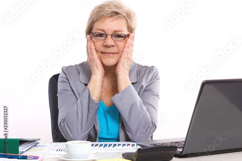 Elderly business woman analyzing financial charts at desk in office