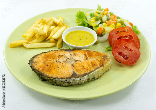 Salmon steak in a green dish on a white background..