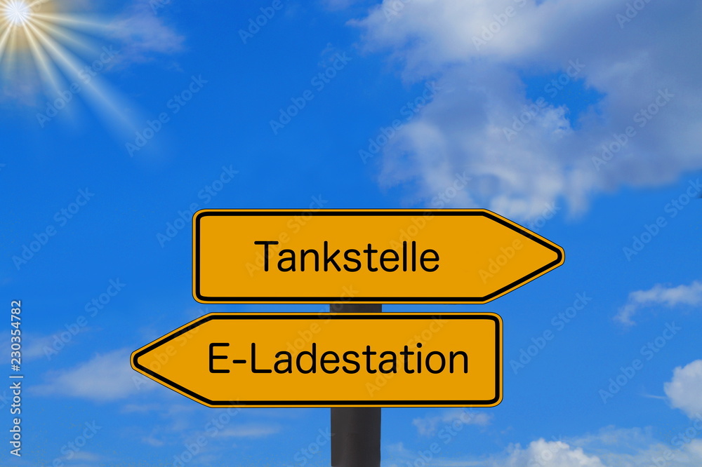 Zwei Schilder weisen auf eine Tankstelle und Ladestation für Elektro Autos Zwei Schilder weisen auf eine Tankstelle und Ladestation für Elektro Autos