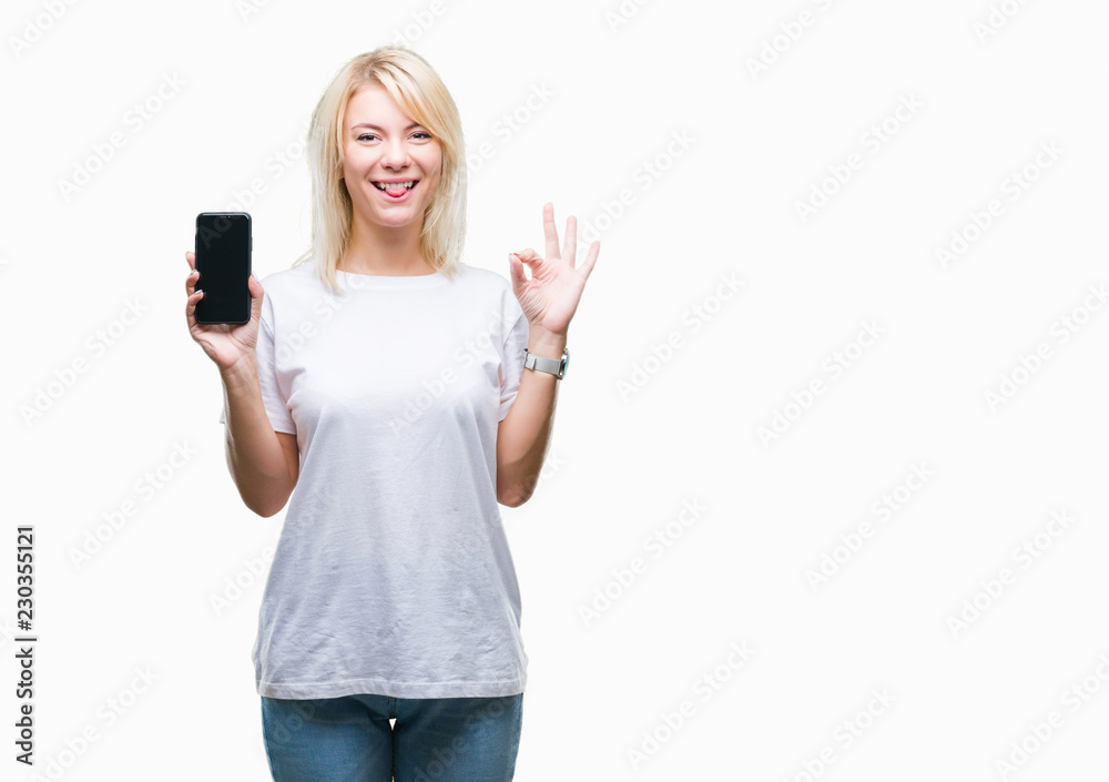 Young beautiful blonde woman showing screen of smartphone over isolated background doing ok sign with fingers, excellent symbol Young beautiful blonde woman showing screen of smartphone over isolated background doing ok sign with fingers, excellent symbol