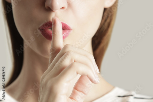 Finger on lips - silent gesture, Woman holding her finger to her lips in a gesture for silence.