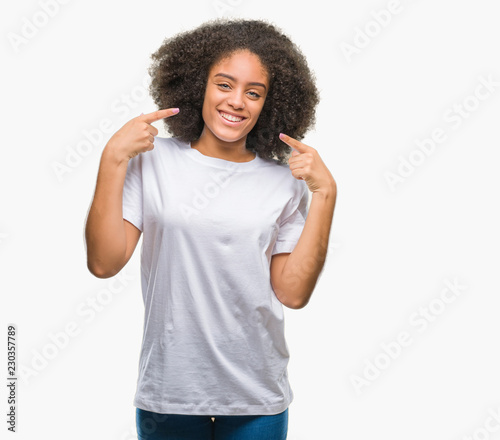 Young afro american woman over isolated background smiling confident showing and pointing with fingers teeth and mouth. Health concept.