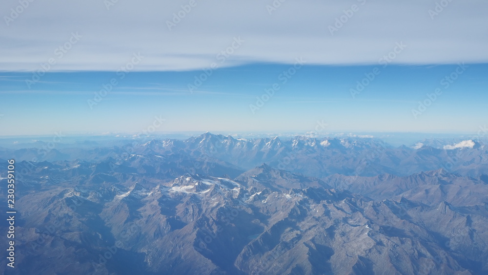 Flying over the European Alps during fall season. Landscape at the Mont Blanc and the glaciers. Aerial view from the airplane window