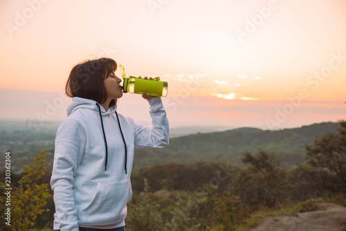 woman drink water from the bottle after exercise on sunrise