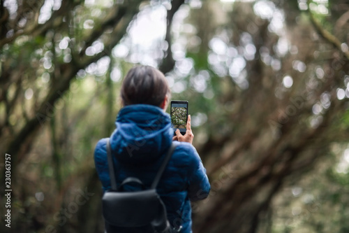 Young traveler woman taking a photo of forest landscape in Anaga Country Park photo